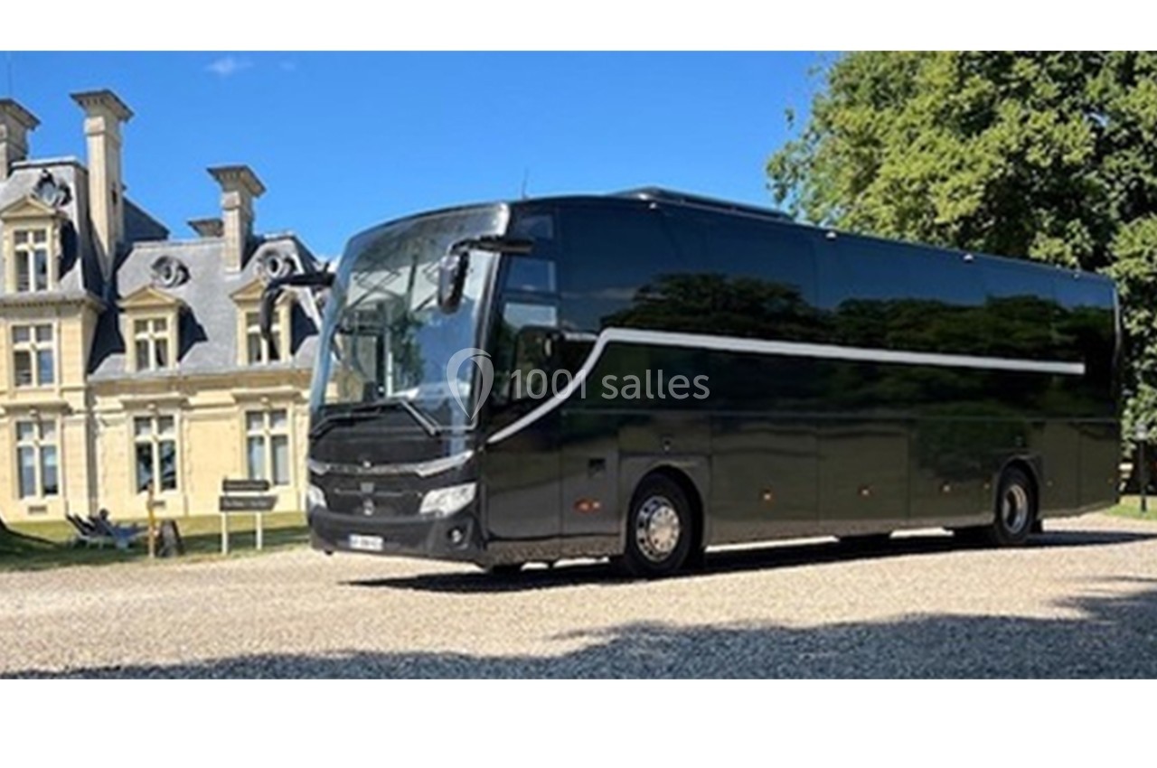 Autocar noir stationné devant un bâtiment de style classique entouré de verdure.
