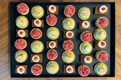 Miniature Traiteur Lyon 2 (Rhône) - Food And Beyond #10 Sandwiches colorés empilés avec des garnitures variées, entourés de roquette et d'olives vertes.