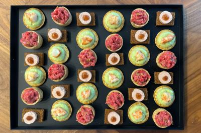 Miniature Traiteur Lyon 2 (Rhône) - Food And Beyond #19 Sandwiches colorés empilés avec des garnitures variées, entourés de roquette et d'olives vertes.