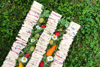 Miniature Traiteur Lyon 2 (Rhône) - Food And Beyond #3 Sandwiches colorés empilés avec des garnitures variées, entourés de roquette et d'olives vertes.