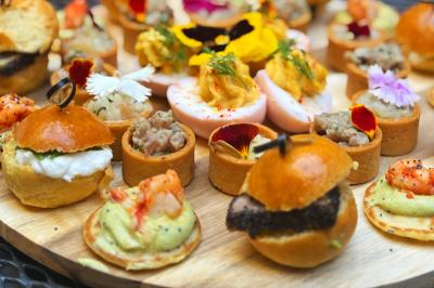 Miniature Traiteur Lyon 2 (Rhône) - Food And Beyond #20 Sandwiches colorés empilés avec des garnitures variées, entourés de roquette et d'olives vertes.