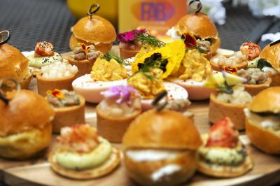 Miniature Traiteur Lyon 2 (Rhône) - Food And Beyond #24 Sandwiches colorés empilés avec des garnitures variées, entourés de roquette et d'olives vertes.