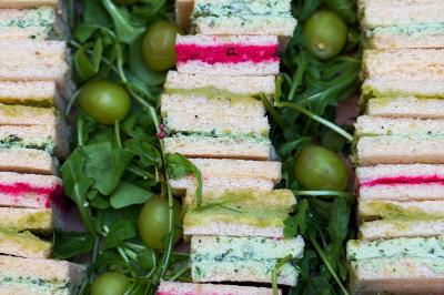 Miniature Traiteur Lyon 2 (Rhône) - Food And Beyond #31 Sandwiches colorés empilés avec des garnitures variées, entourés de roquette et d'olives vertes.