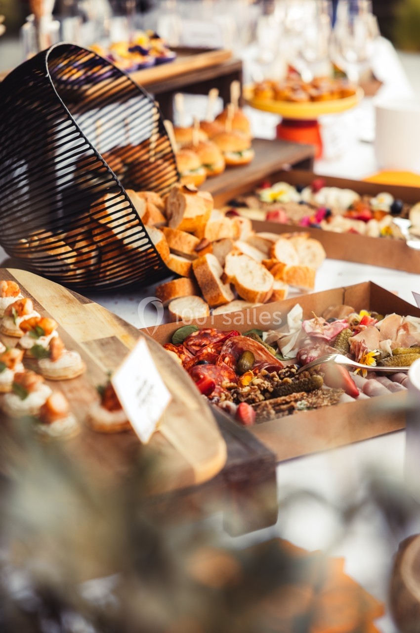 Buffet varié avec pains, légumes, canapés et autres plats disposés sur des plateaux en bois.