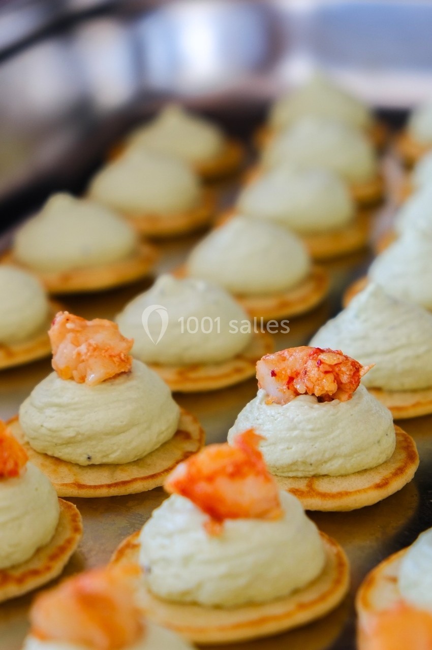 Petits canapés garnis de mousse verte et de morceaux de homard, disposés sur un plateau en métal.