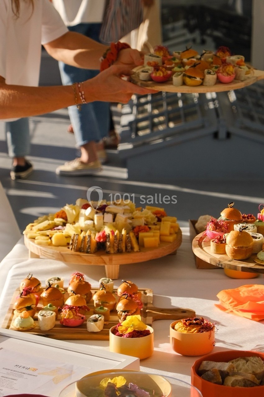 Plateaux de bouchées apéritives variées, incluant fromages, sushis et petits pains, présentés sur une table.