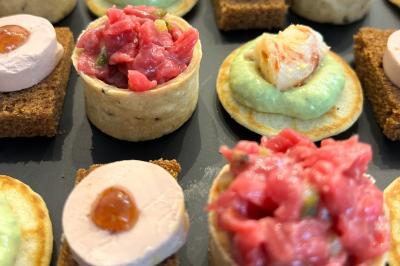 Sandwiches colorés empilés avec des garnitures variées, entourés de roquette et d'olives vertes.