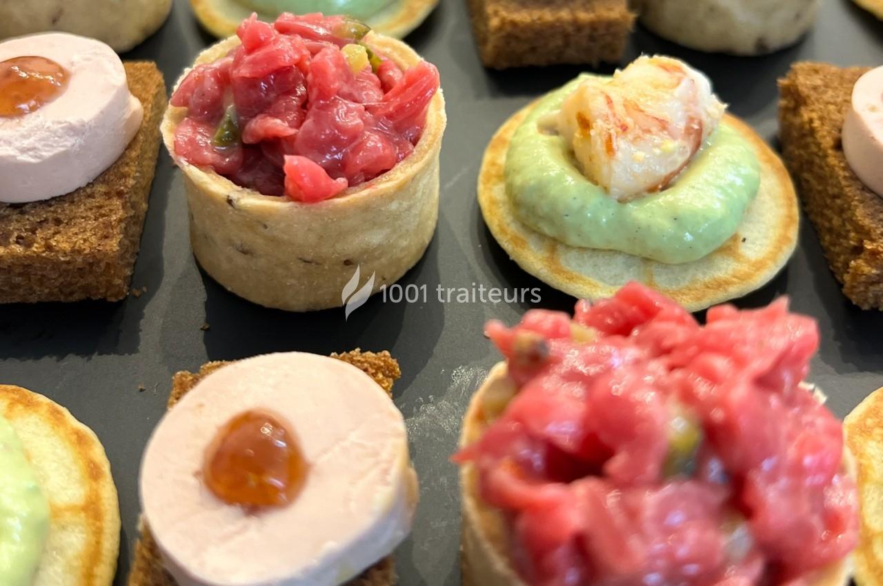Assortiment de canapés variés avec tartare, mousse de foie et crème verte sur différentes bases.