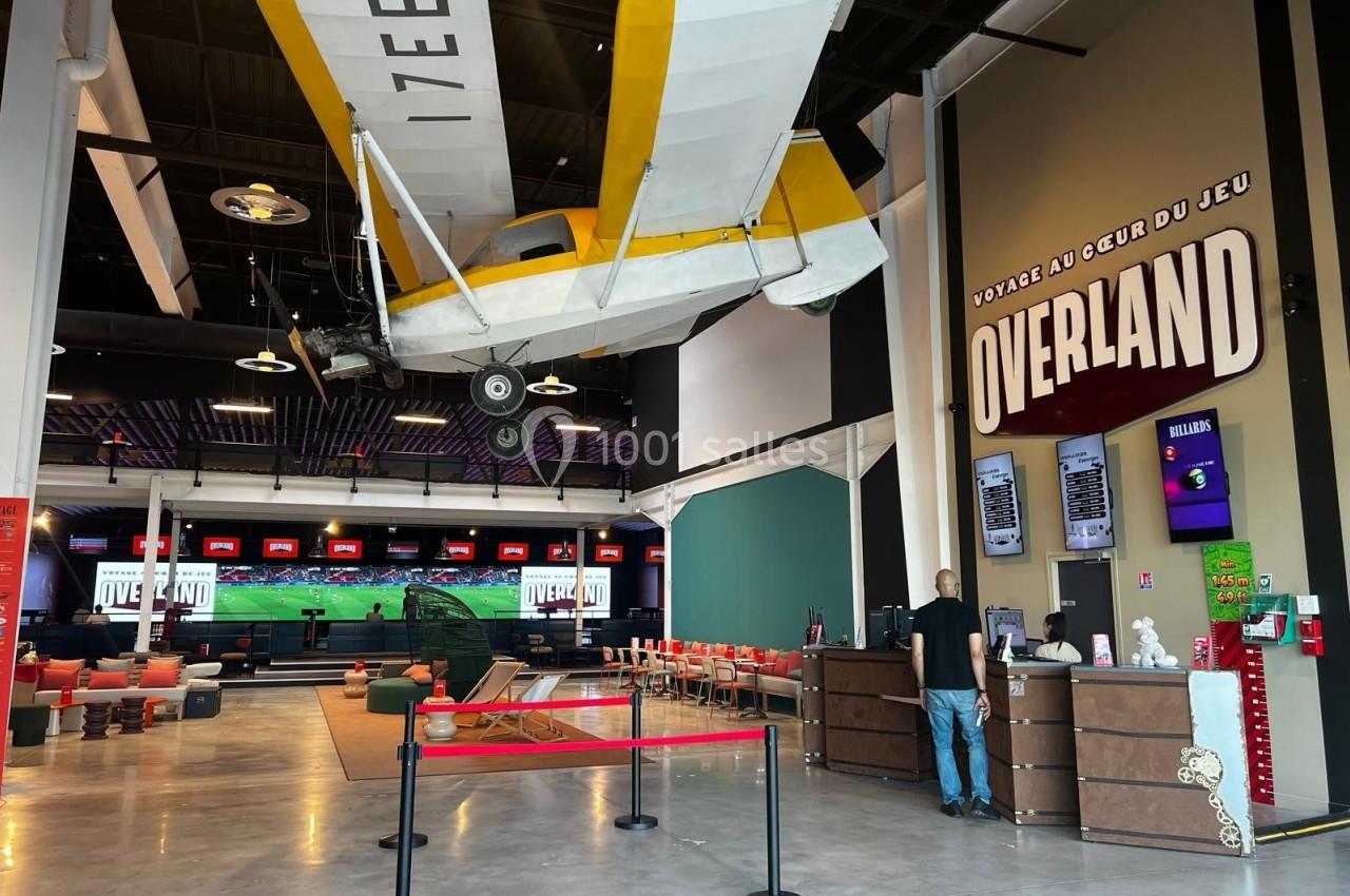 Un avion suspendu dans un espace intérieur moderne avec un comptoir, des écrans et des sièges.