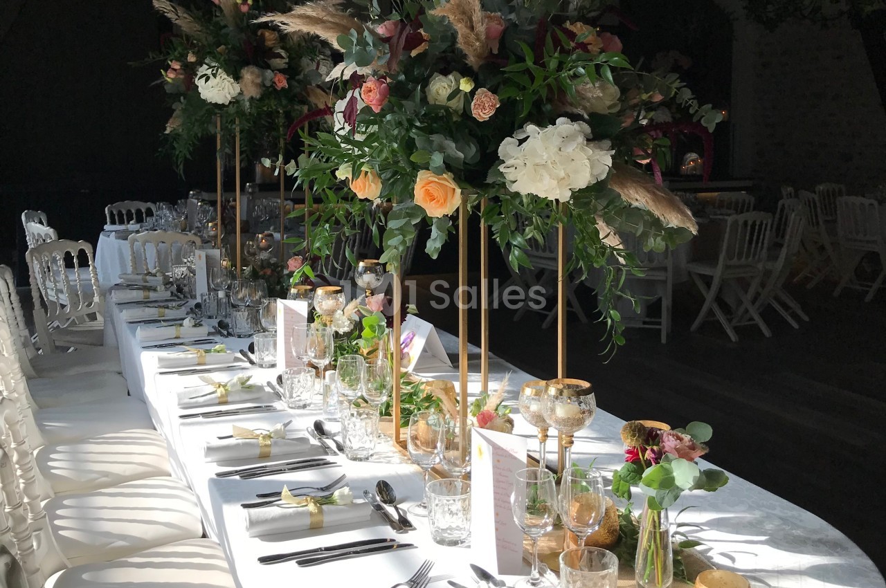 Table de réception élégamment décorée avec des fleurs colorées sur des supports dorés et une vaisselle raffinée.