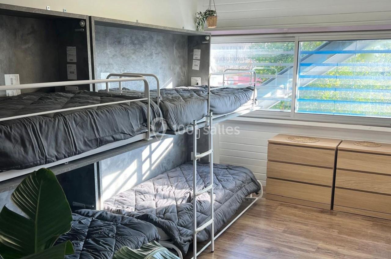 Lit superposé dans une chambre lumineuse avec parquet, grande fenêtre et commodes en bois clair.