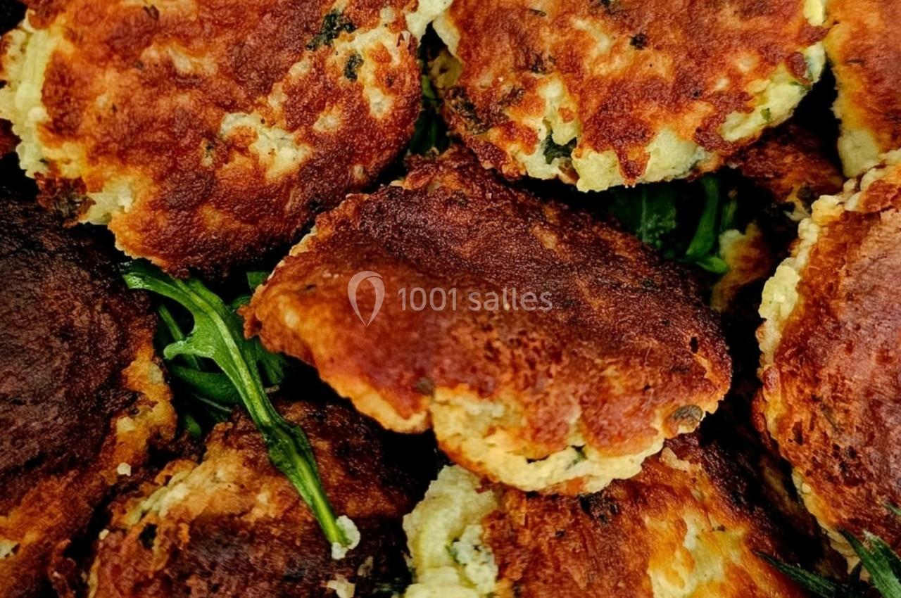 Galettes dorées aux herbes disposées sur un lit de roquette avec quelques tomates cerises.