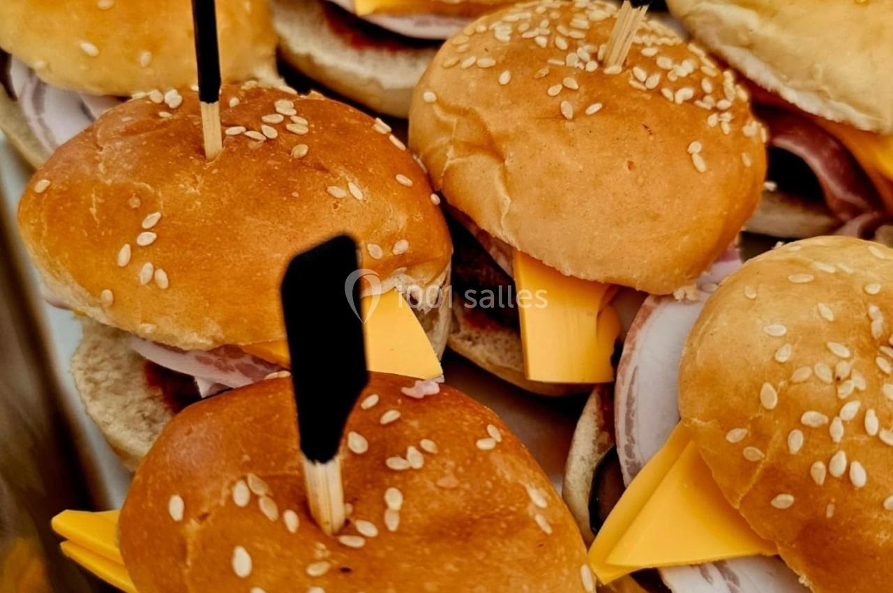Mini burgers garnis de fromage, jambon et piques en bois, disposés dans un plateau en métal.