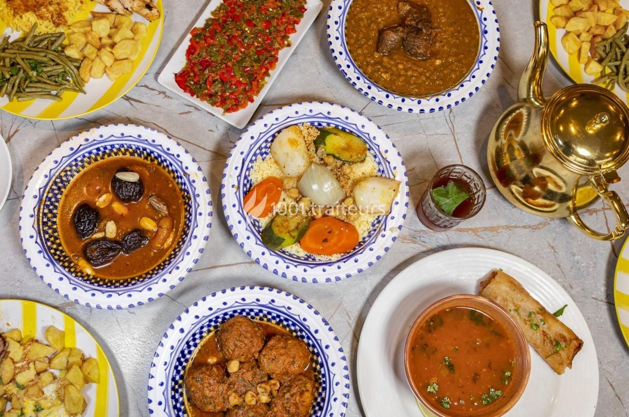 Table garnie de plats traditionnels variés, incluant tajines, légumes, soupe, théière dorée et accompagnements.
