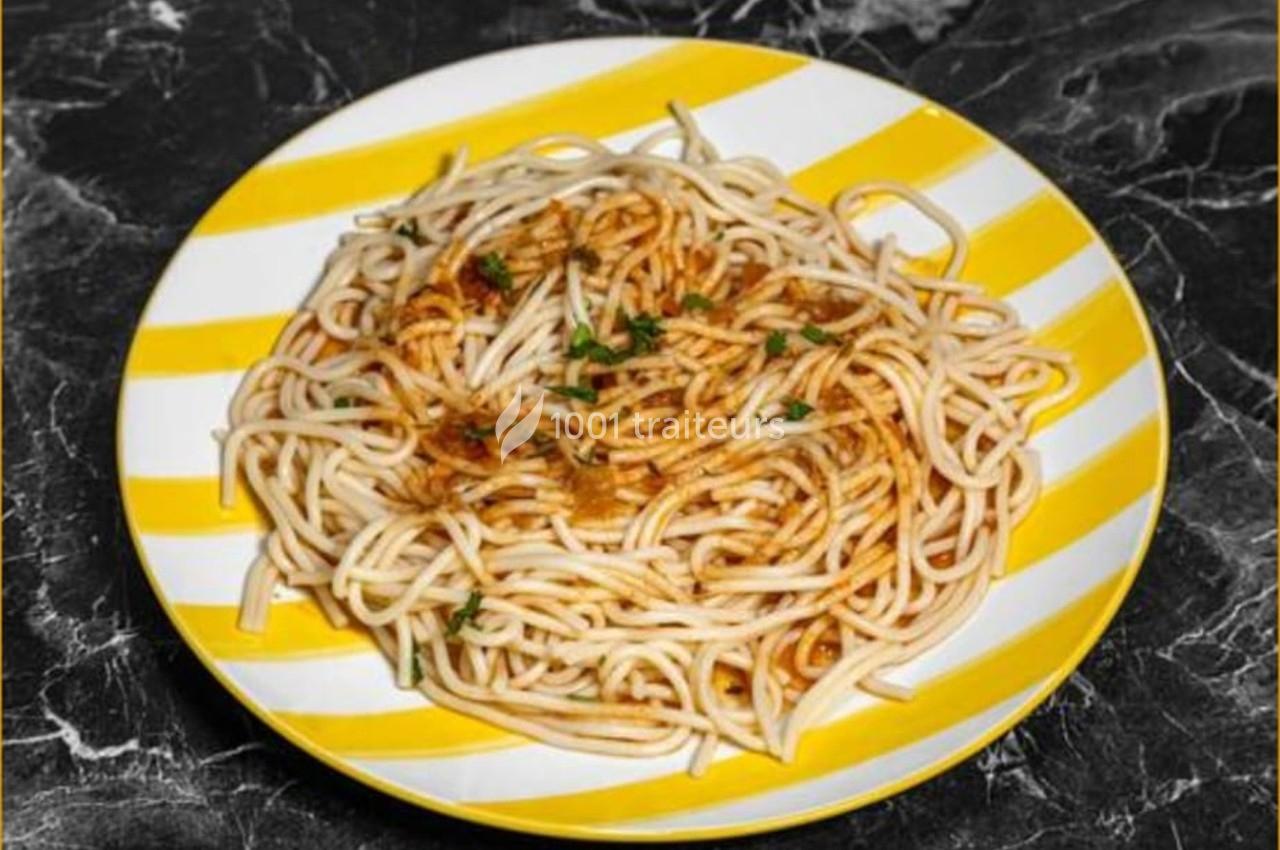 Assiette de spaghettis avec sauce tomate et persil, servie sur une assiette rayée jaune et blanche.