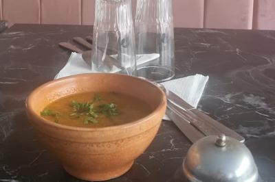 Miniature Traiteur Nanterre (Hauts-de-Seine) - Le Désiré de la Méditerranée #30 Bol de soupe garnie de coriandre sur une table en marbre avec des couverts, des verres et une salière en arrière-plan.