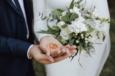 Un couple habillé élégamment se regarde avec tendresse entre deux rideaux blancs.