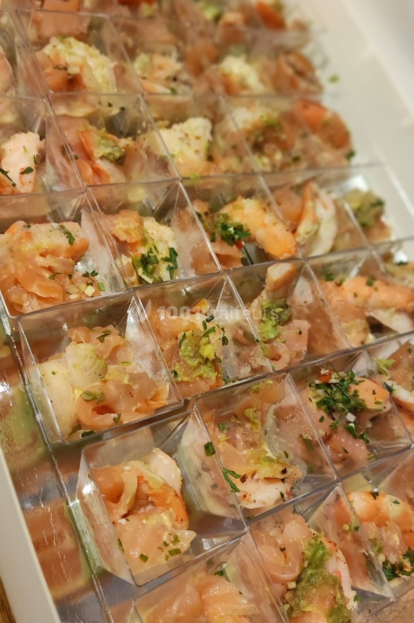 Assortiment de verrines contenant des crevettes, du saumon et des herbes fraîches, présenté dans un plateau.