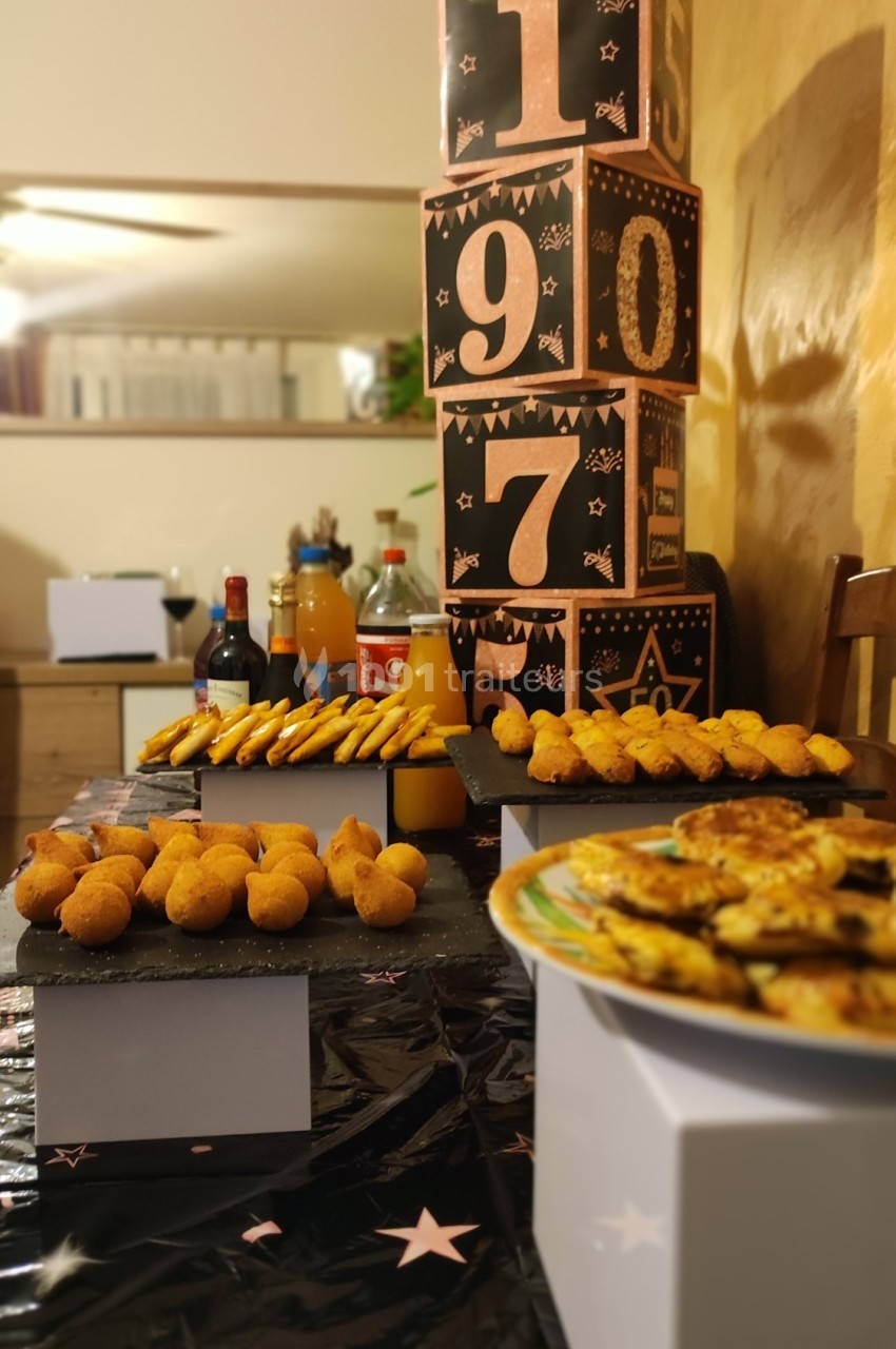 Table décorée avec des amuse-bouches, des boissons et des cubes numérotés en arrière-plan pour une fête.