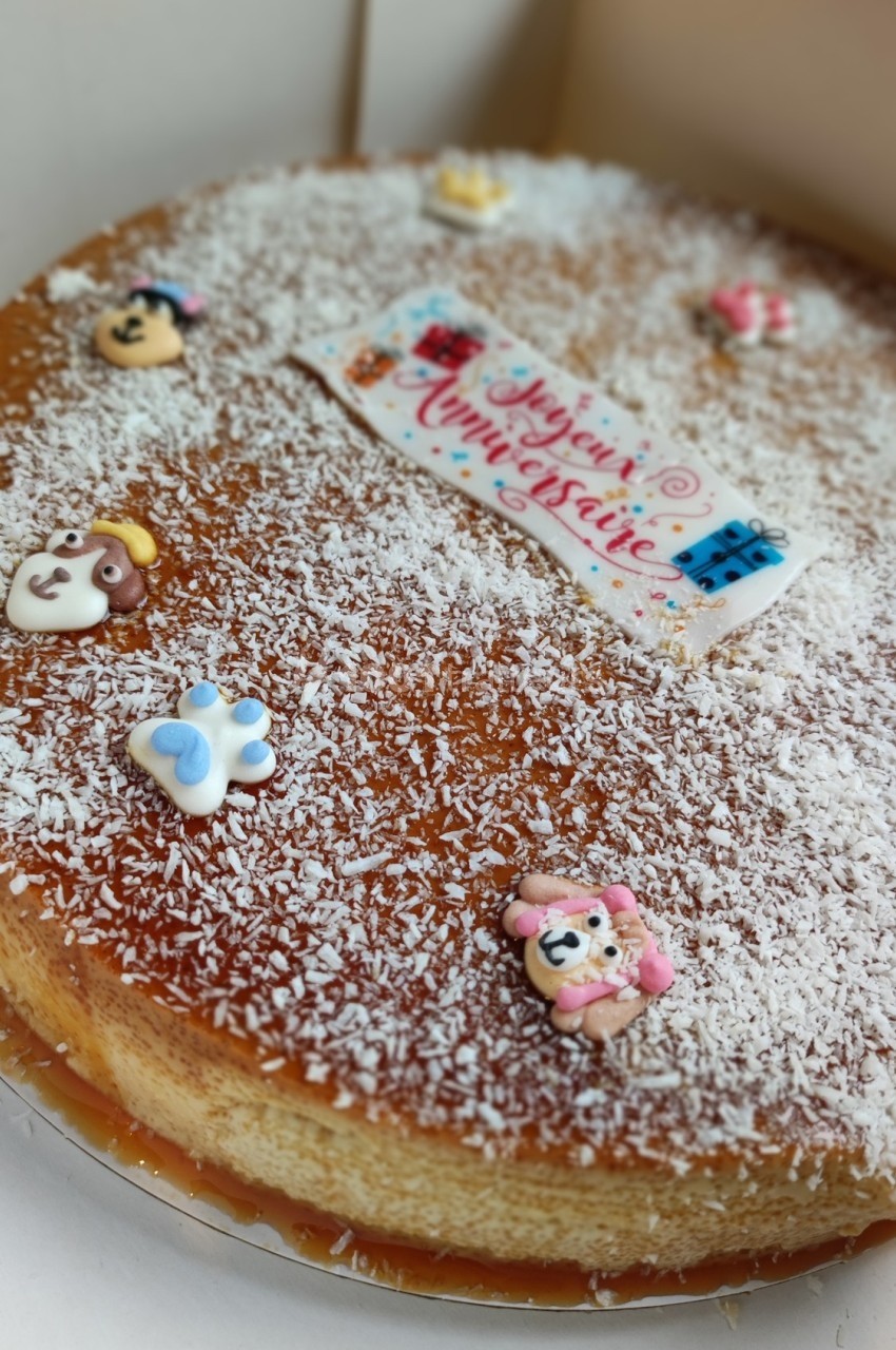 Gâteau décoré de sucre râpé, figurines colorées et une plaque ’Joyeux Anniversaire’ en sucre.