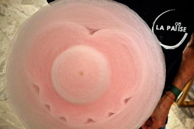 Barbe à papa rose en forme de fleur tenue par une personne portant un t-shirt noir.