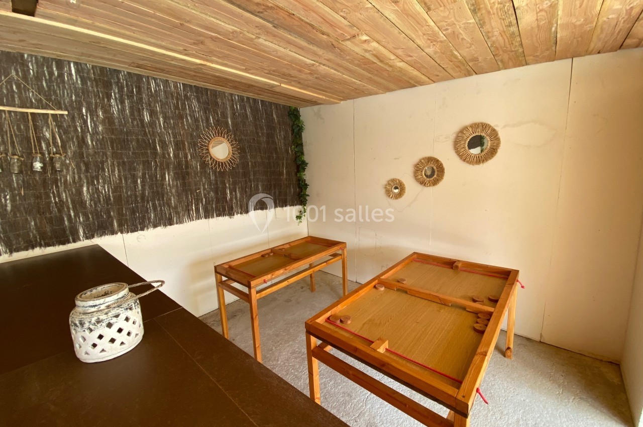 Deux tables en bois dans une pièce décorée de miroirs ronds, avec un plafond en bois et un mur sombre à gauche.