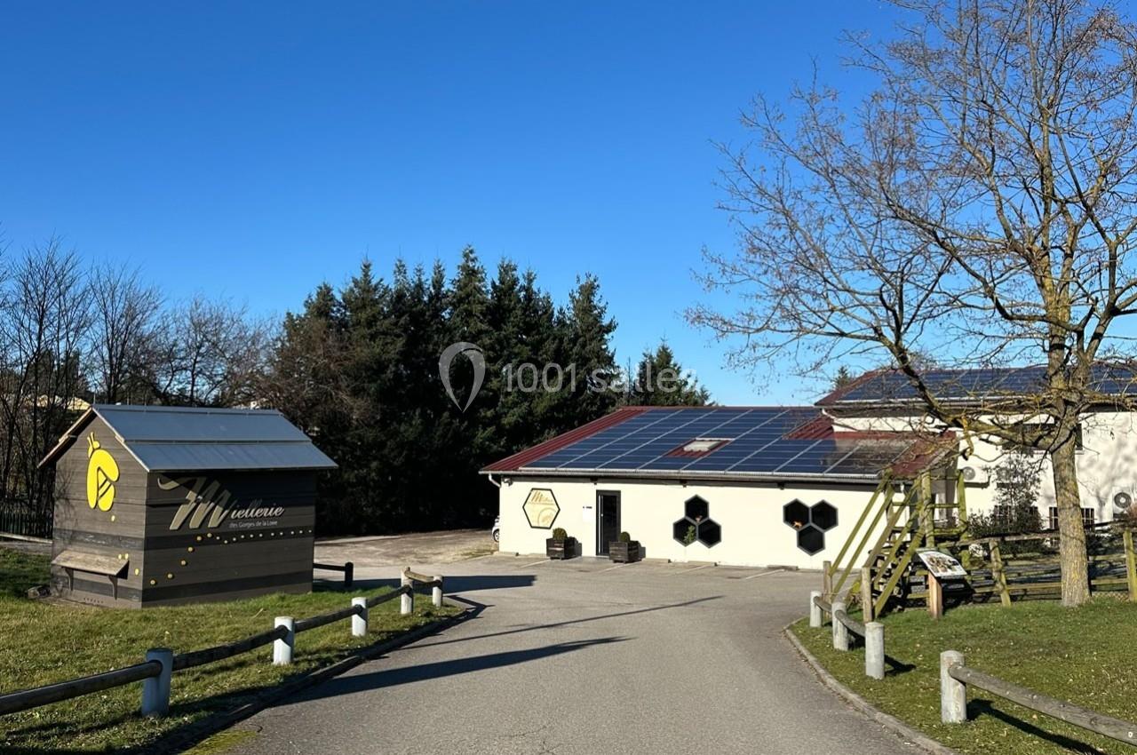 Bâtiments avec panneaux solaires sur le toit, entourés d'arbres et d'une route sous un ciel bleu dégagé.