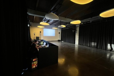 Salle sombre avec deux écrans affichant un paysage désertique, éclairages colorés et mobilier minimaliste.