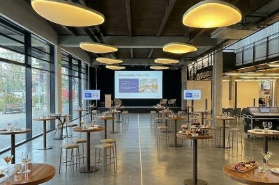 Façade vitrée d'un bâtiment moderne avec des drapeaux suspendus et une entrée visible au rez-de-chaussée.