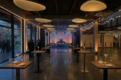 Façade vitrée d'un bâtiment moderne avec des drapeaux suspendus et une entrée visible au rez-de-chaussée.