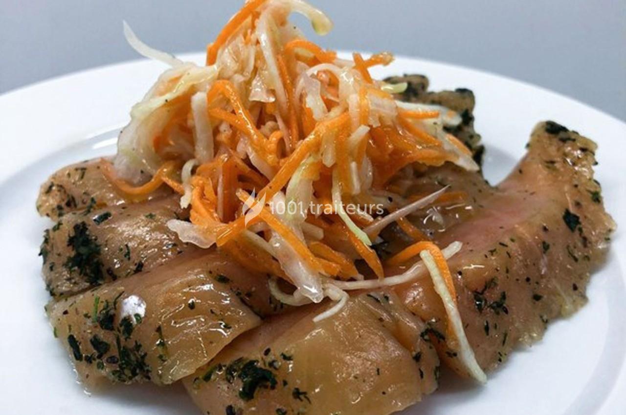 Tranches de poisson mariné garnies de salade de chou et carottes sur une assiette blanche.