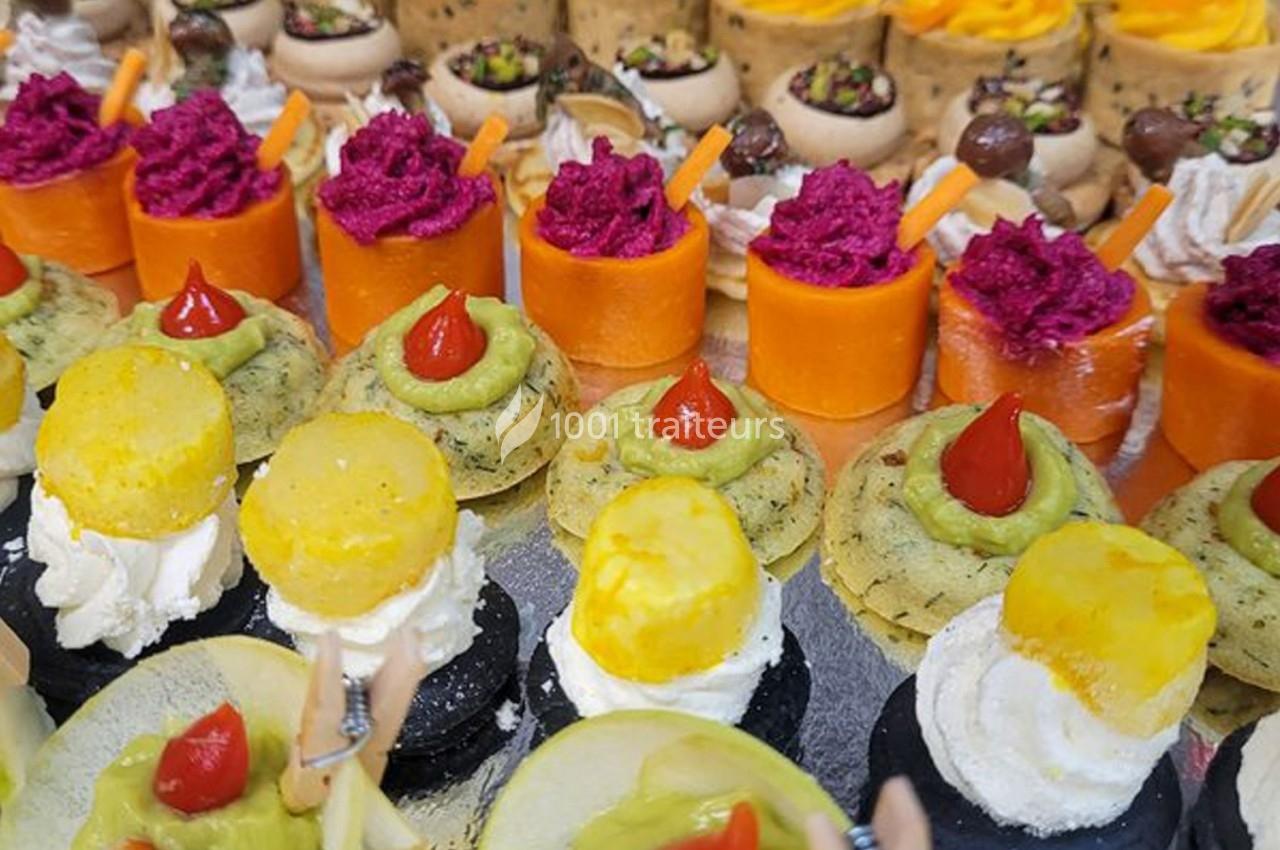 Assortiment de bouchées apéritives colorées, composées de légumes, fromage et purées variées, disposées sur un plateau.