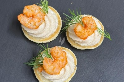 Plateau de bouchées apéritives garnies de mousse rose et décorées de feuilles de persil, disposées sur une grille.
