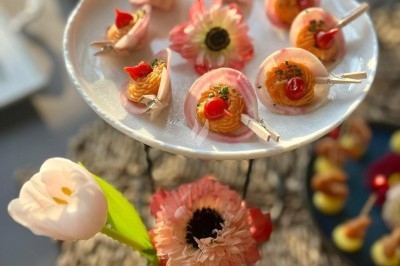 Plateau de bouchées apéritives garnies de mousse rose et décorées de feuilles de persil, disposées sur une grille.