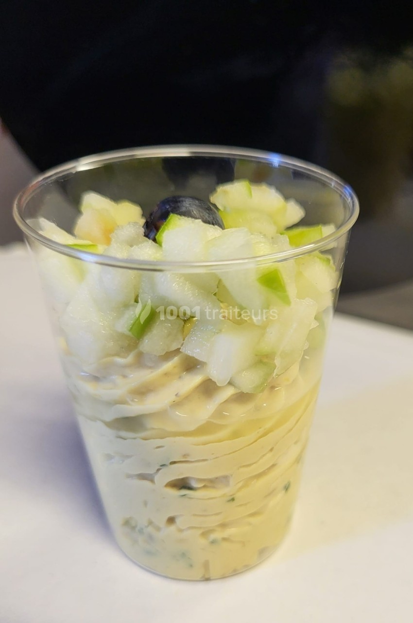 Verrine contenant une mousse crémeuse garnie de dés de pomme verte et d'une myrtille.