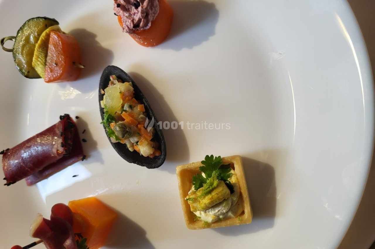 Assortiment de bouchées apéritives variées disposées sur une assiette blanche.