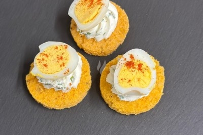 Plateau de bouchées apéritives garnies de mousse rose et décorées de feuilles de persil, disposées sur une grille.