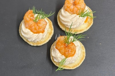 Plateau de bouchées apéritives garnies de mousse rose et décorées de feuilles de persil, disposées sur une grille.