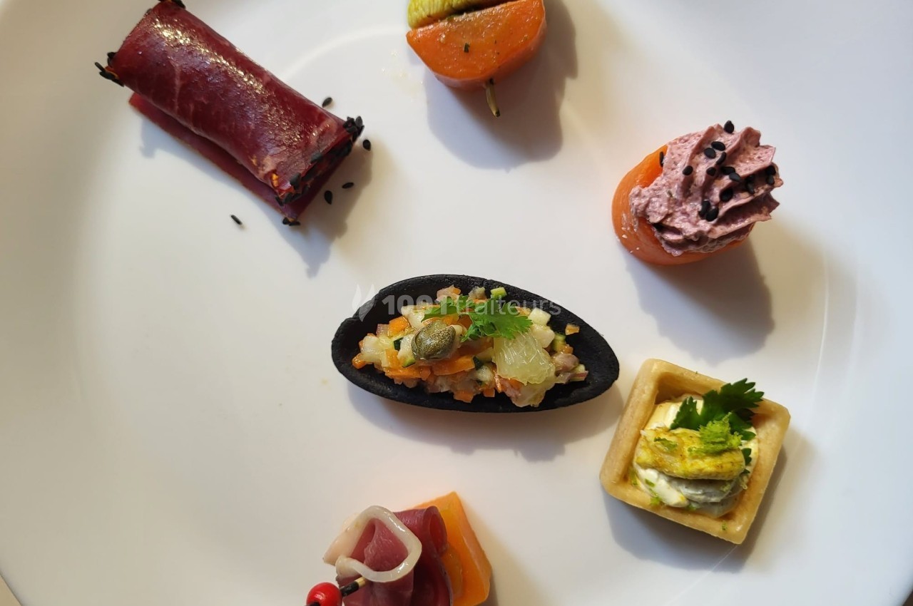 Assortiment de bouchées apéritives variées disposées sur une assiette blanche.