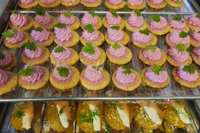 Plateau de bouchées apéritives garnies de mousse rose et décorées de feuilles de persil, disposées sur une grille.