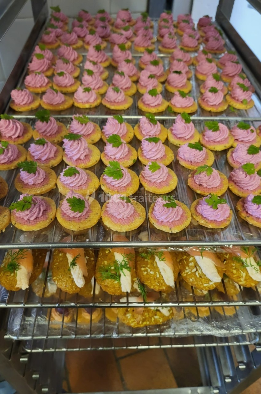 Plateaux de bouchées apéritives garnies de mousse rose et de persil, et de roulés au saumon et aneth.