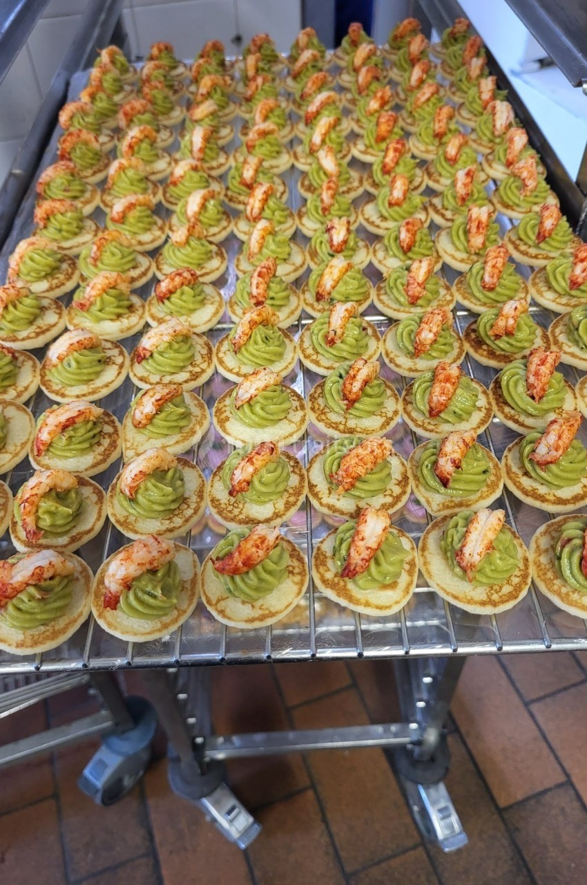 Plateau de bouchées apéritives garnies de mousse verte et de morceaux de crustacés, disposées en rangées.