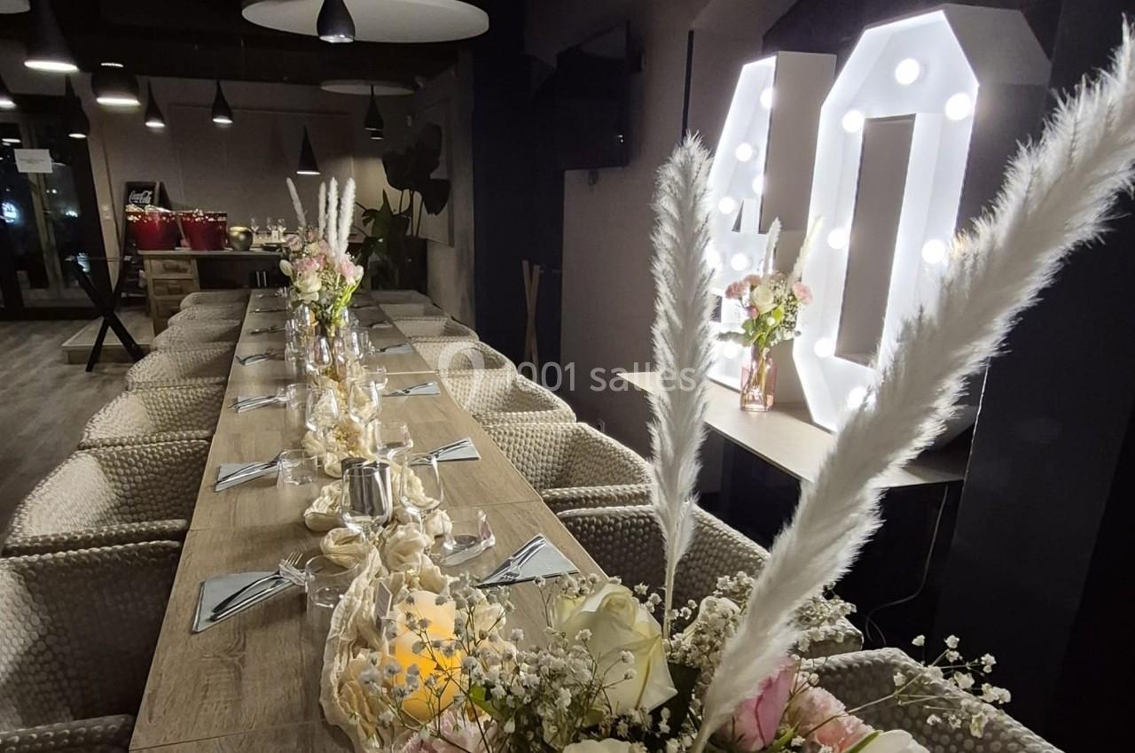 Table décorée pour un événement, avec fleurs, bougies et chiffres lumineux ’40’ en arrière-plan.