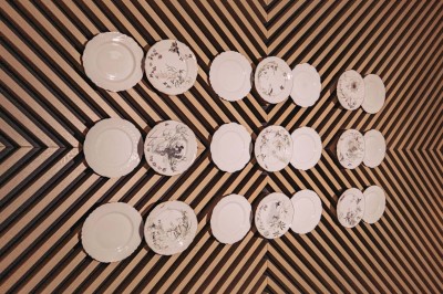 Fleurs blanches en céramique fixées sur un mur rouge, formant une composition artistique.