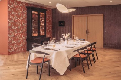 Vue aérienne d'une terrasse animée entourée de vignes au coucher du soleil, avec des invités profitant du cadre.