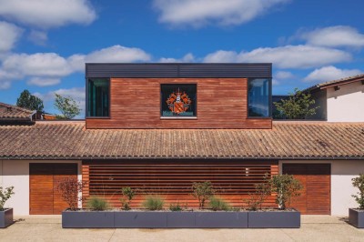 Vue aérienne d'une terrasse animée entourée de vignes au coucher du soleil, avec des invités profitant du cadre.