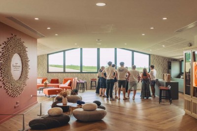 Vue aérienne d'une terrasse animée entourée de vignes au coucher du soleil, avec des invités profitant du cadre.