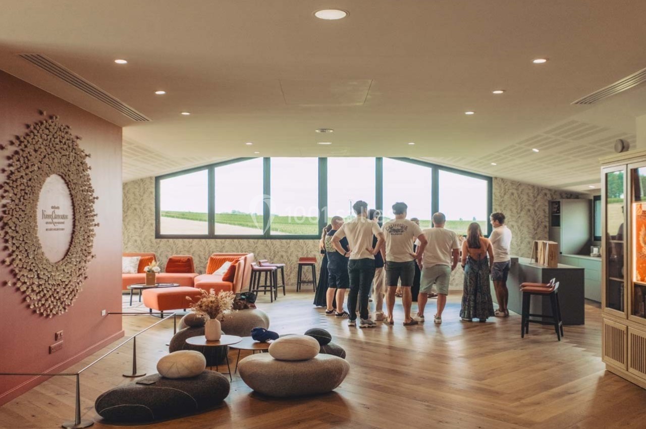Un groupe de personnes debout dans une salle lumineuse avec de grandes fenêtres donnant sur un paysage champêtre.