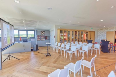 Vue aérienne d'une terrasse animée entourée de vignes au coucher du soleil, avec des invités profitant du cadre.