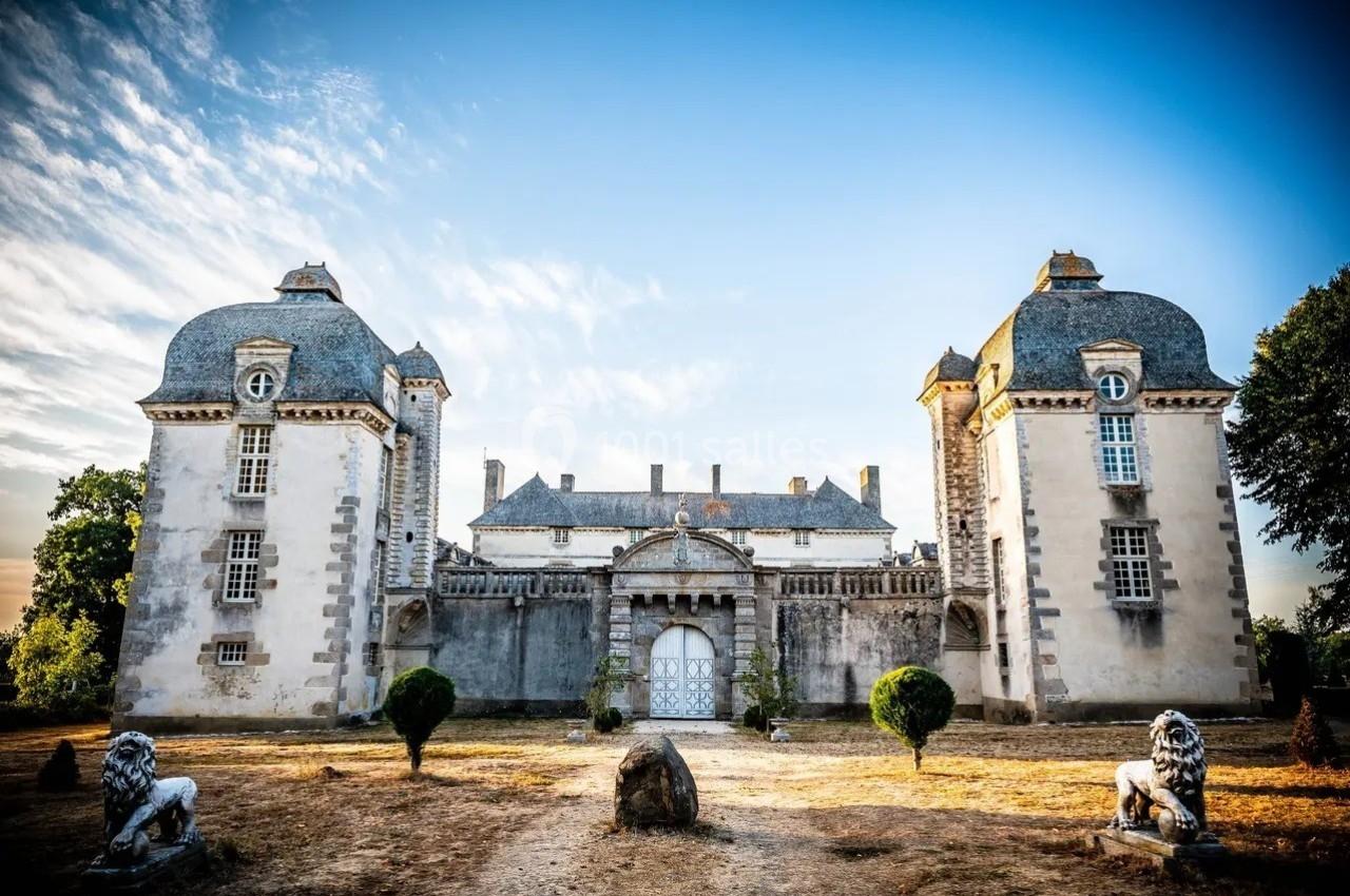 Façade d'un château ancien avec deux tours symétriques, une grande porte centrale et un ciel dégagé en arrière-plan.